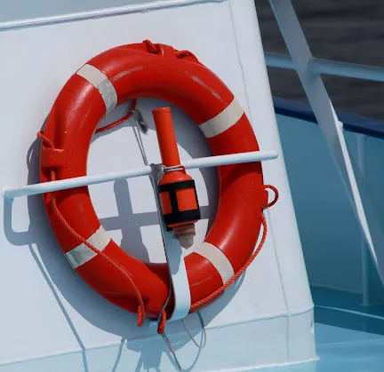 An orange floatation device to prevent drownings and an electric torch stowed on a boat