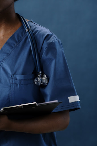 A healthcare professional in blue scrubs holding a medical clipboard