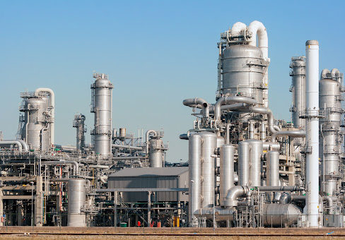Silver colored pipes and tanks shining in the sun at an oil refinery 