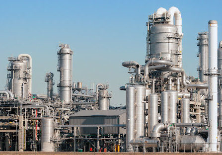 An industrial plant with silver silos and pipes shining in the sun