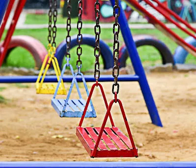 Three swings in bright colors at an outdoor playground