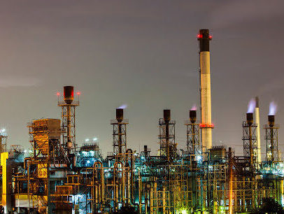 An industrial plant light up against a darkening sky