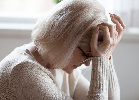 A visibly distraught woman with her head in her hands experiencing pain and suffering.