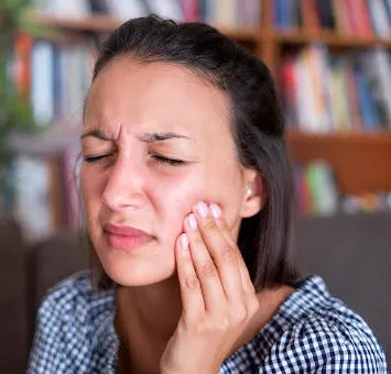 A woman holding her cheek, expressing tooth pain
