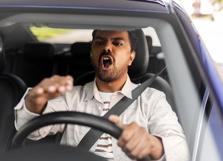 An angry man behind the wheel of a car driving recklessly