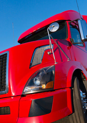 A closeup of the front end of a red semi truck