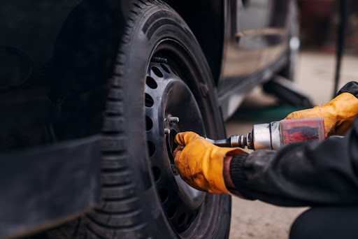 A mechanic with orange gloves changing a tire