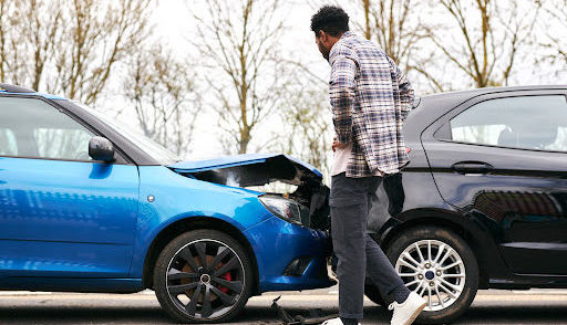 A young man inspects the damage from an accident with an uninsured motorist