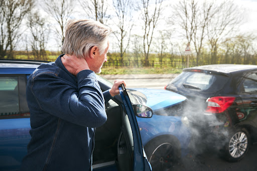 An injured man holds his neck after experiencing whiplash from a car wreck