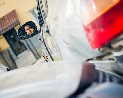 A woman looks in her rear-view mirror in disbelief after a car accident in a parking lot