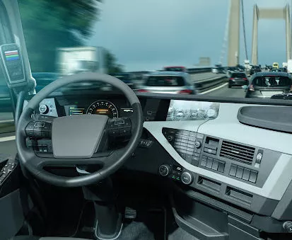 An interior view of the dashboard of a self driving truck approaching a bridge