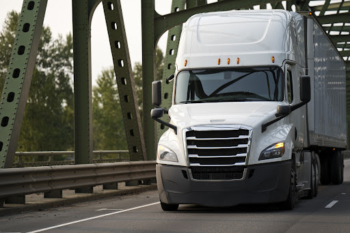 A heavy white semi truck crossing a bridge