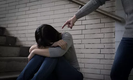 A girl crying while being pointed at and bullied in a stairwell