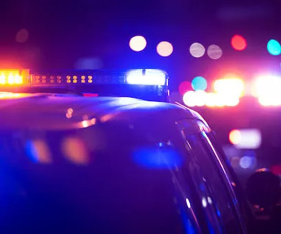 Blue, red, and orange lights from police cars responding to a crime scene at night