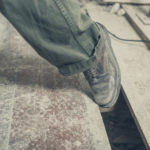 The foot of a person tripping on a gap between the floor boards in a room undergoing renovations