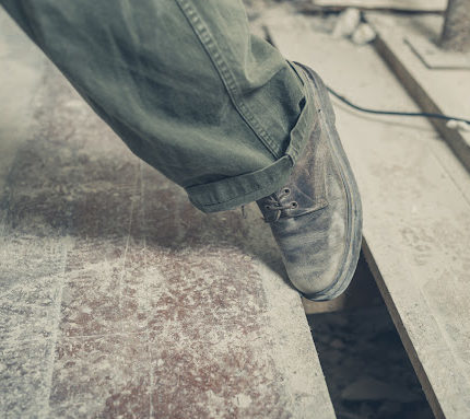 A person's foot getting caught in a gap between floorboards