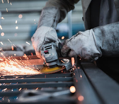 An industrial worker using a grinder on metal creating a spray of sparks