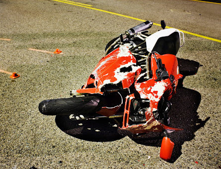 A heavily damaged motorcycle resting on the pavement following an accident