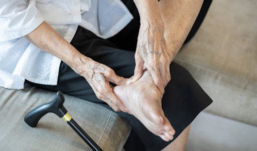 A nursing home resident inspects their foot for injuries