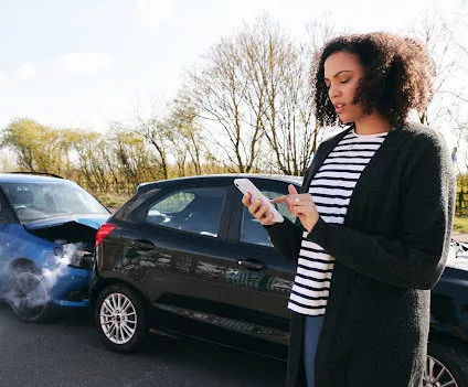 A young woman using her phone to contact a car accident lawyer in Shreveport after a rear end collision