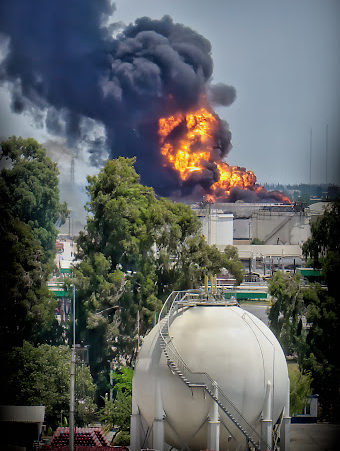 A large plume of smoke and flame in the distance from a plant explosion