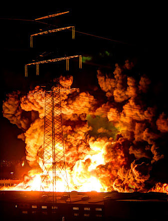 An explosion and plumes of smoke at a plant at night