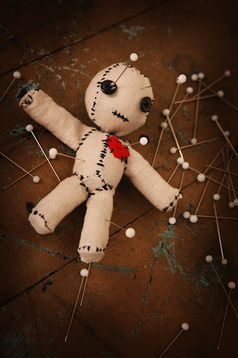 A voodoo doll with pins sticking out
