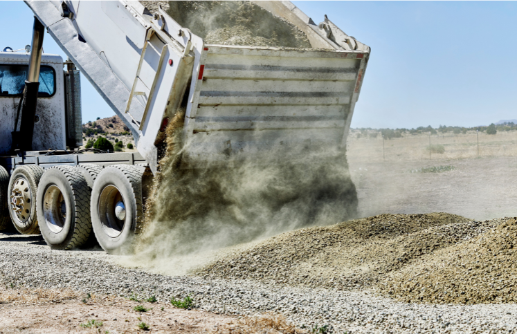 loose gravel pouring from dump truck in gravel field