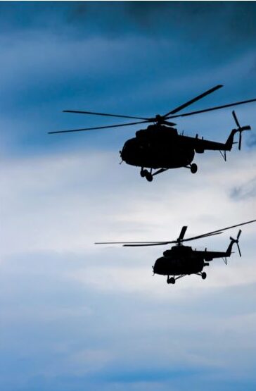 two helicopters flying at dusk