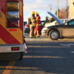 ambulance and wrecked car surrounded by workers and people