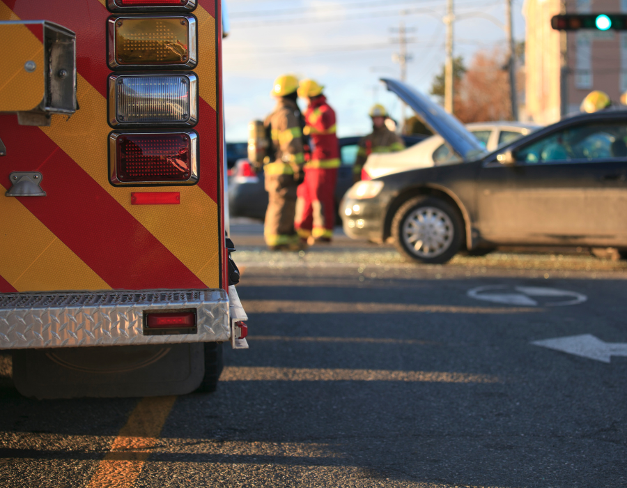 ambulance and wrecked car surrounded by workers and people