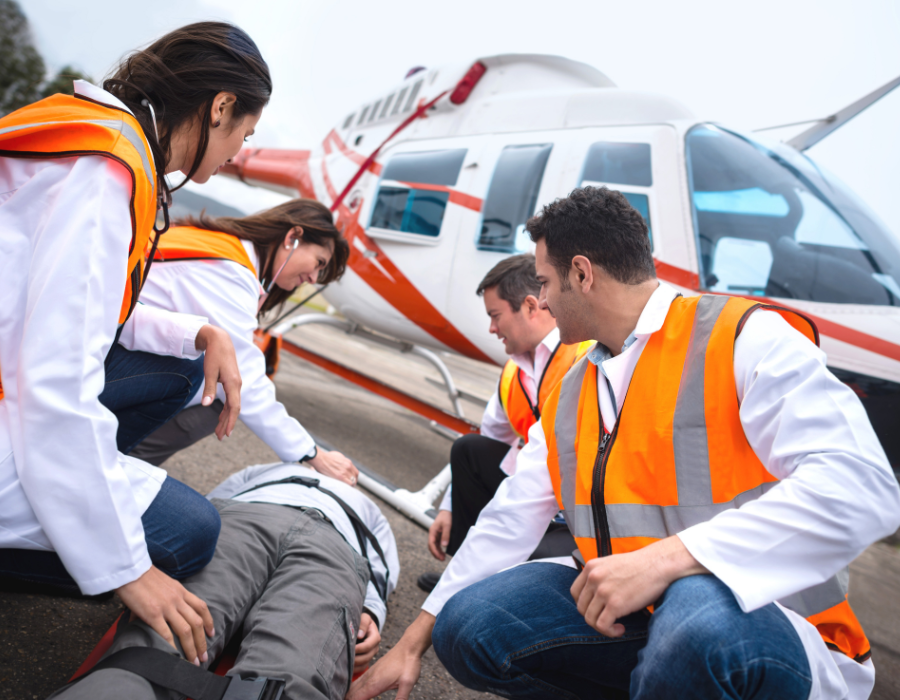 team of medics surrounding patient next to air ambulance