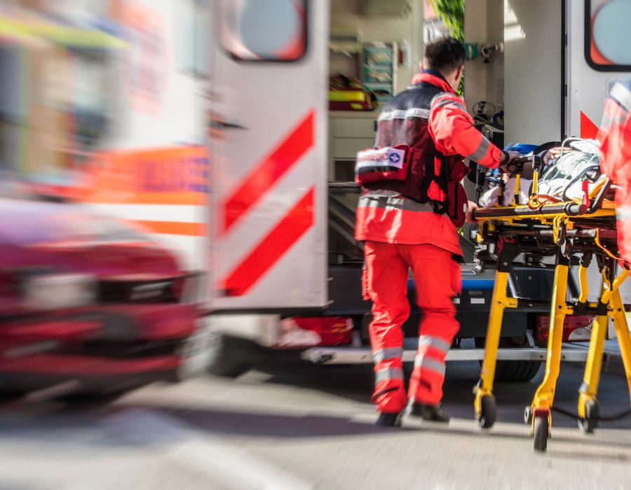 Major car crash indicated with blurred car and ambulance taking driver in stretcher