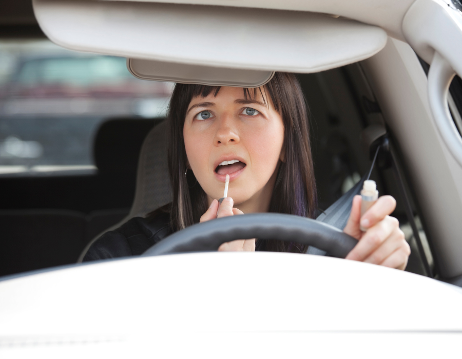 lady putting on lip gloss while driving