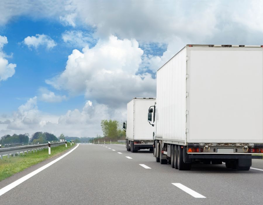 2 white trucks driving down highway