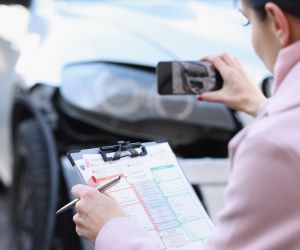 woman taking pictures of car damage and writing down the details