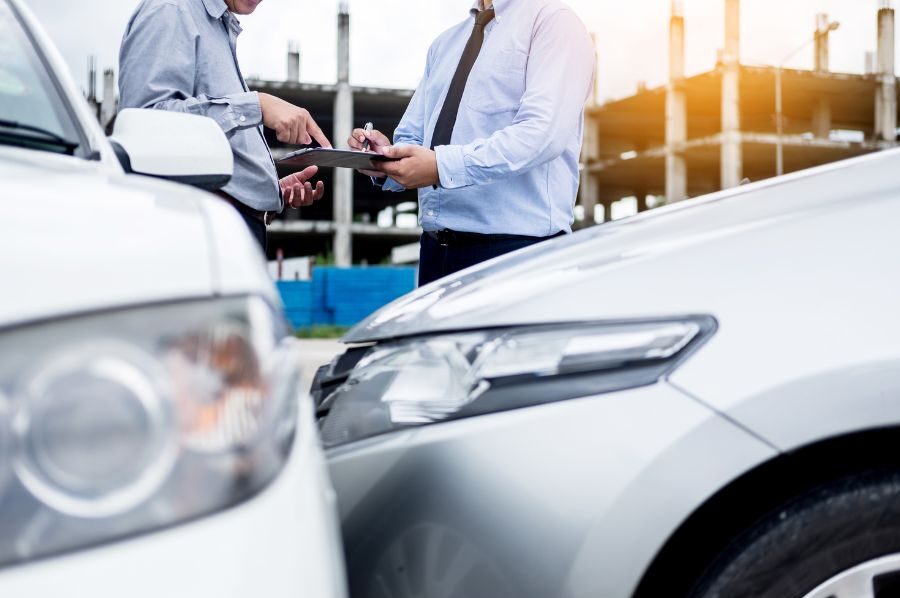 men discussing and signing paperwork after accident