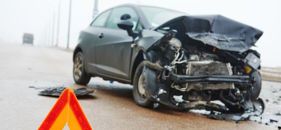 front of black car crushed on side of highway
