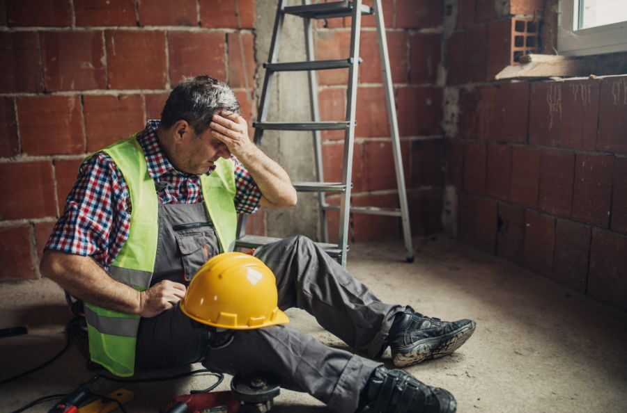 man holding head on ground at work