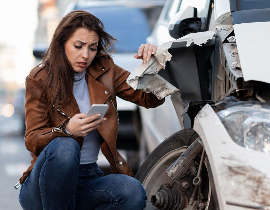 woman in distress holding destroyed car