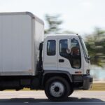 side angle shot of commercial truck driving on highway