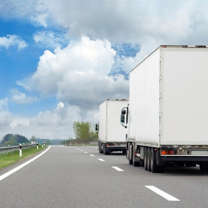 2 white trucks driving down highway 2 white trucks driving down highway