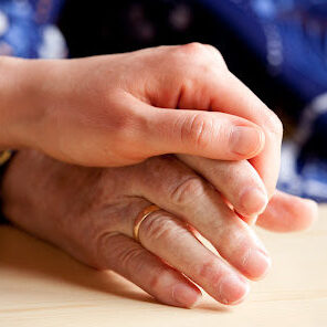 A young hand comforts and elderly hand A young hand comforts and elderly hand