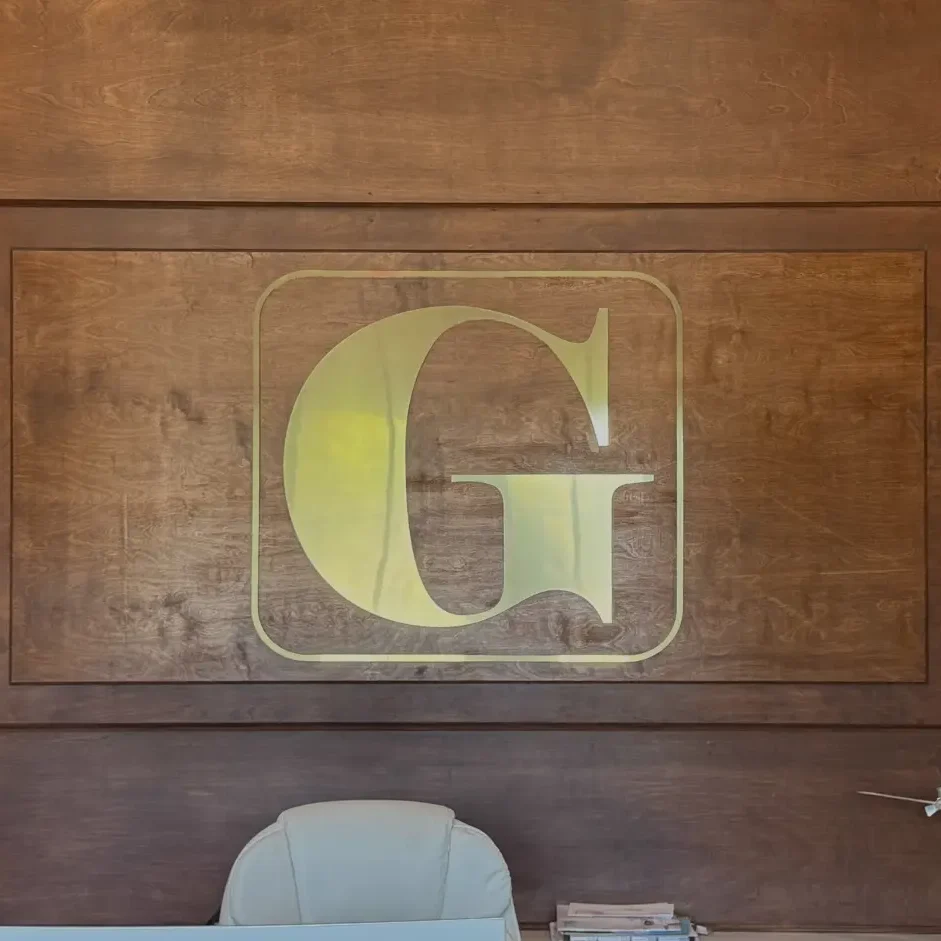 Houma Office Large Gold G on Dark wood wall