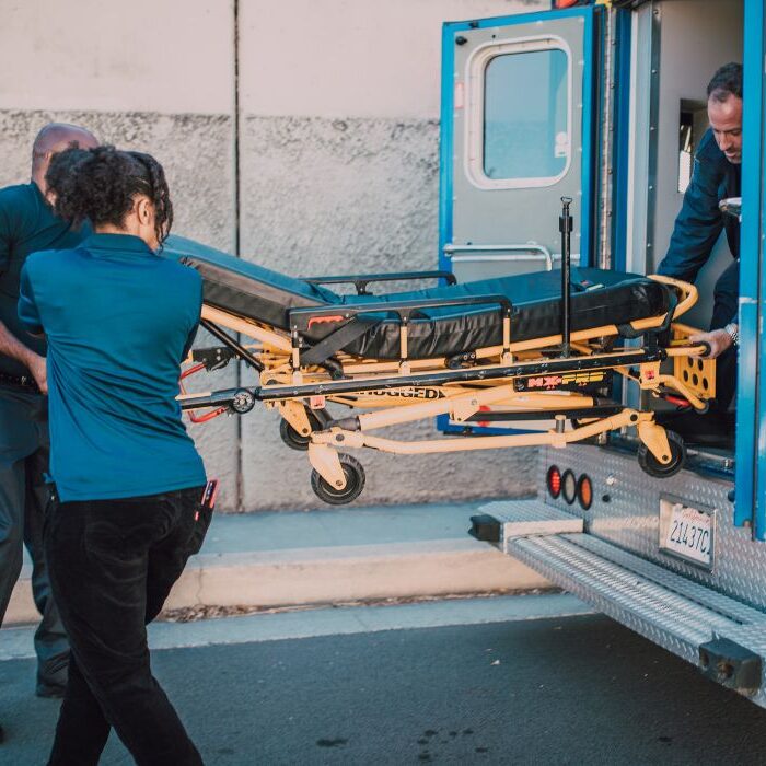 medical personnel deploying a stretcher for a severely injured individual
