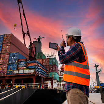 Maritime-Worker dock manager on walkie talkie to manage crane