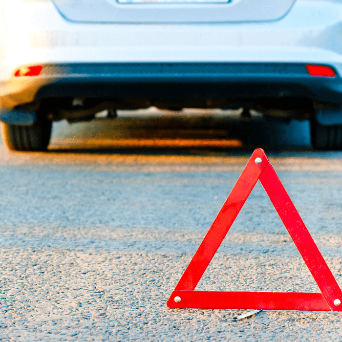 car on side of road with hazard sign