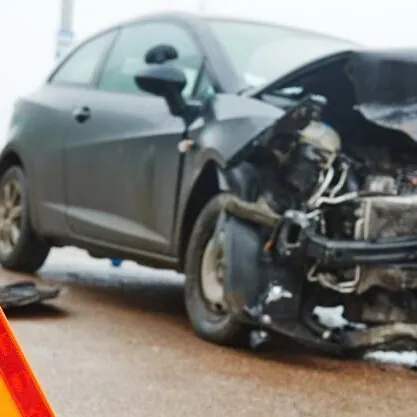 front of black car crushed on side of highway front of black car crushed on side of highway